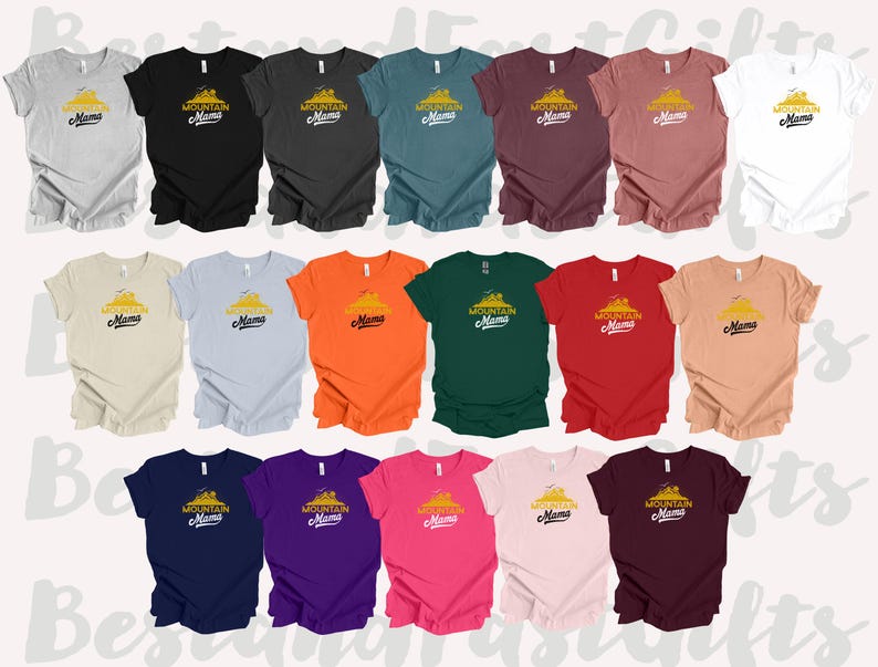 May include: A collection of short-sleeved t-shirts in various colors, each featuring the text "Mountain Mama" with a mountain graphic in yellow and black. Colors include gray, black, teal, burgundy, and white.