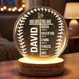 May include: A glowing, spherical night light with the name "David" and inspirational text. The light is set on a wooden base with a Bible verse. The sphere features a cross and a dove design, with the words "Chosen", "Child of God", "Strong", "Fearless", and "Hope".