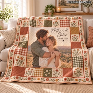 May include: A patchwork quilt featuring a central photograph of a couple embracing, with the text "Nathan & Chloe 08.16.2026". The quilt is composed of squares in shades of orange, green, and white, decorated with floral patterns and gingham checks.
