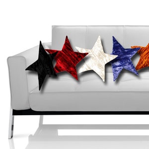 May include: A white leather sofa with nine star-shaped decorative pillows in various colors, including black, red, white, blue, orange, and gold. The pillows are arranged across the back of the sofa.