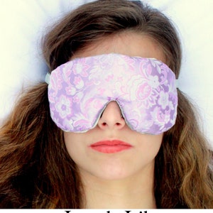 May include: A purple and white floral eye mask with a satin-like texture. The eye mask is designed to block out light and promote sleep.