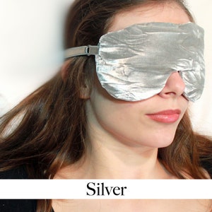 K&ouml;nnte beinhalten: Eine silberne Schlafmaske mit geknitterter Textur. Die Maske ist aus weichem Stoff und hat ein elastisches Band.