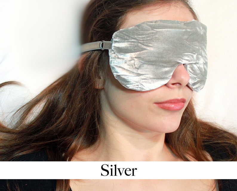 K&ouml;nnte beinhalten: Eine silberne Schlafmaske mit geknitterter Textur. Die Maske ist aus weichem Stoff und hat ein elastisches Band.
