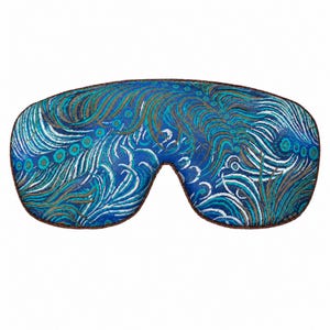 May include: A contoured sleep mask featuring a vibrant blue, teal, and brown abstract pattern of swirling lines and circular motifs. The mask has a dark brown piped edge that outlines the entire shape, providing a defined border for the design.