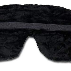 K&ouml;nnte beinhalten: Schwarze Schlafmaske mit verstellbarem Gummiband. Die Maske ist aus weichem, pl&uuml;schem Stoff.