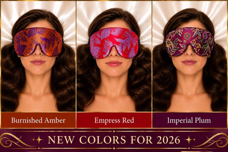 May include: Three sleep masks featuring floral patterns in Burnished Amber, Empress Red, and Imperial Plum. Each mask has a contoured shape and an elastic strap. The text at the bottom reads NEW COLORS FOR 2026, with labels for each color variant.