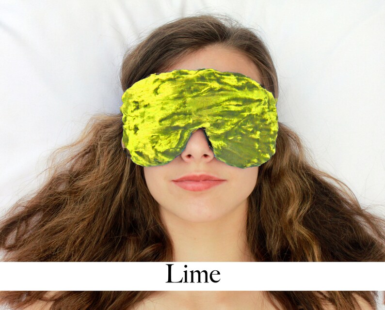 K&ouml;nnte beinhalten: Eine Schlafmaske aus weichem Samt in Limettengr&uuml;n. Die Maske wird von einer Person getragen, die auf einem wei&szlig;en Bett liegt.