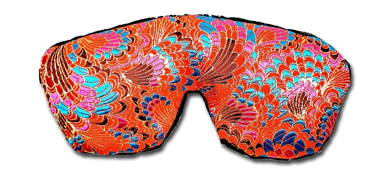 May include: An eye mask featuring a bright orange fabric with a detailed floral design in pink, blue, and brown. The mask has a black trim and is designed to block out light.