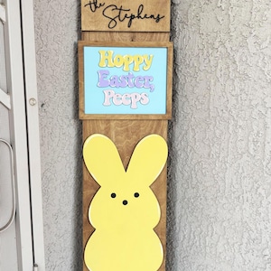 May include: Wooden Easter sign with a yellow, pink, and blue bunny cutout. The sign says "Hoppy Easter, Peeps" and "Welcome" with the family name "The Stephens" at the top.