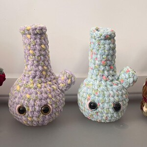 May include: Four crocheted plush bongs with googly eyes. The bongs are in different colors and patterns: red, purple and yellow, blue and white, and brown, green, and white.