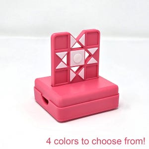 May include: A pink plastic game with a white star design. The game is made up of squares and triangles. The game is on a base.