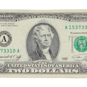 May include: A two-dollar bill featuring a portrait of Thomas Jefferson. The bill is primarily green and black, with the text "TWO DOLLARS" prominently displayed. The serial number is A 15373310 A.