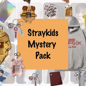 以下が含まれることがあります： Stray Kidsをテーマにしたミステリーアイテムのコレクション。グレーのフード付きスウェットシャツには「Dominant」と「Stray Kids」の文字が書かれており、写真フレーム付きのぬいぐるみキーホルダー、小さなノート、バンドメンバーの写真がついたキーホルダーが含まれています。