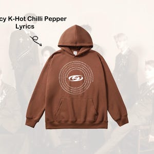May include: Brown hooded sweatshirt with a white graphic design featuring a circle with text and a logo. The text reads "Bouncy K-Hot Chilli Pepper Lyrics".