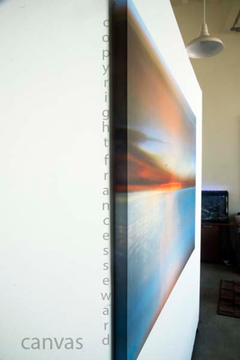 K&ouml;nnte beinhalten: Ein gro&szlig;es abstraktes Leinwandbild mit einem Farbschema in Blau, Orange und Wei&szlig;. Das Bild h&auml;ngt an einer wei&szlig;en Wand.