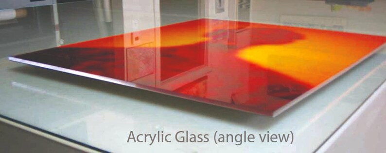 K&ouml;nnte beinhalten: Eine rote und orangefarbene Acrylglasscheibe mit einem verschwommenen Bild einer Personensilhouette. Die Scheibe ist schr&auml;g gestellt und scheint auf einer Glasoberfl&auml;che zu liegen.