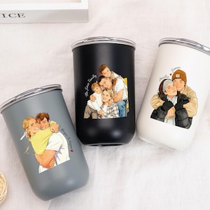 Pode incluir: Três canecas de aço inoxidável com ilustrações de famílias. As canecas são cinza, pretas e brancas. Cada caneca tem uma tampa prateada. As ilustrações retratam casais e famílias se abraçando. O texto está incluído.