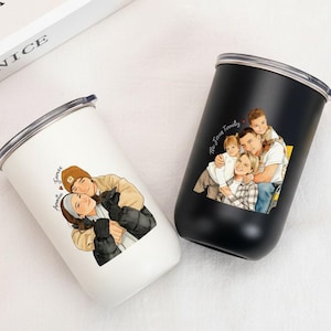 Pode incluir: Dois copos de aço inoxidável, um branco e outro preto, com bordas e tampas prateadas. O copo branco apresenta uma ilustração de casal com o texto "Amelia James". O copo preto tem um retrato de família com o texto "The James Family".