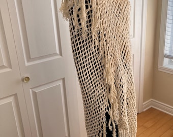 May include: A cream-colored crochet shawl with fringe. The shawl is draped over a mannequin.