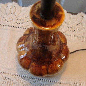 May include: A brown ceramic table lamp base with a scalloped design. The base has a glossy finish and a dark brown glaze.