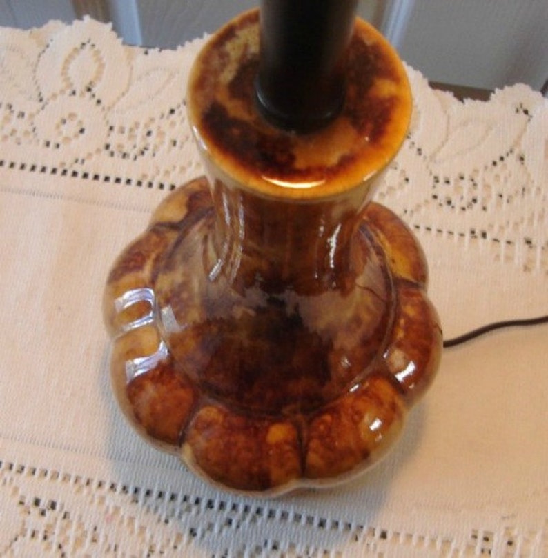 May include: A brown ceramic table lamp base with a scalloped design. The base has a glossy finish and a dark brown glaze.