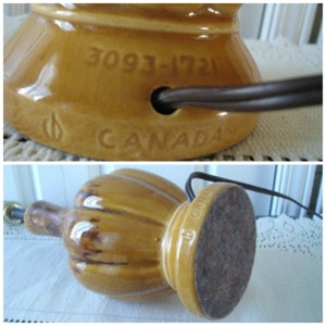May include: A brown ceramic table lamp with a ribbed design and a round base. The lamp has a cord and a plug. The base is marked with the number "3093-1721" and the word "CANADA".