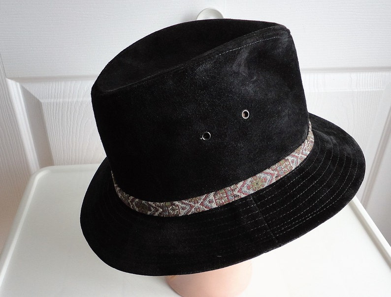 May include: A black suede fedora hat with a brown and white patterned band.