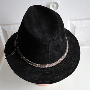 May include: A black suede fedora hat with a brown and white patterned band around the crown.