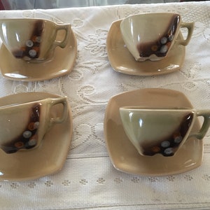May include: Set of four brown and green ceramic teacups and saucers with a geometric design. The cups and saucers have a brown and white speckled glaze.