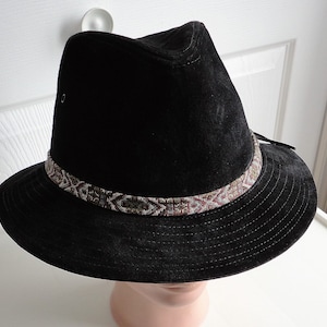 May include: A black suede fedora hat with a brown and white patterned band.
