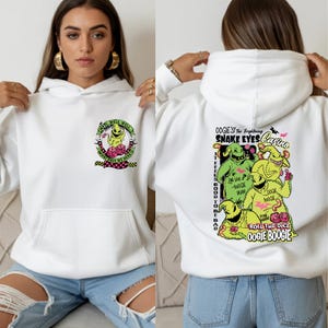 May include: White hoodie featuring a graphic of Oogie Boogie from The Nightmare Before Christmas. The front has a small design, while the back displays a larger, colorful illustration with text including "Snake Eyes Casino" and "Roll the Dice".