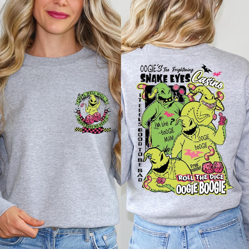 May include: A heather gray sweatshirt featuring a colorful graphic of Oogie Boogie from The Nightmare Before Christmas. The front has a small design, while the back displays a larger, detailed image with text including "Snake Eyes Casino."