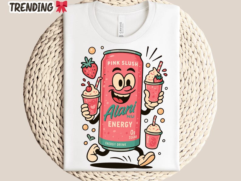 May include: White t-shirt featuring a cartoon pink energy drink can with a smiling face, holding two strawberry slushies. The can reads "Pink Slush" and "Alani Nu Energy 0g Sugar". The shirt has the word "TRENDING" at the top.