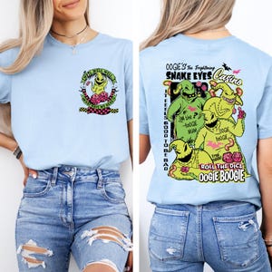 May include: Light blue t-shirt featuring Oogie Boogie from The Nightmare Before Christmas. The front graphic includes text "Well, Well, Well, What Have We Here?". The back graphic features Oogie Boogie and text "Oogie's Too Frightening Snake Eyes Casino".
