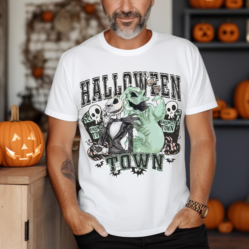 May include: A white short-sleeve t-shirt featuring a graphic print of Jack Skellington and Oogie Boogie from The Nightmare Before Christmas. The design includes the text HALLOWEEN TOWN, skulls, and bats, set against a distressed background.