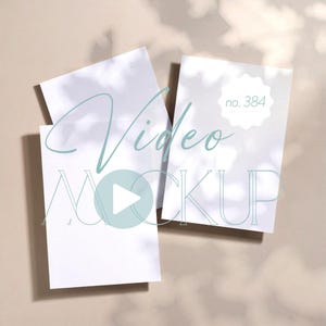 Puede incluir: Tres tarjetas rectangulares blancas dispuestas sobre una superficie beige, con sombras y las palabras "Video MOCKUP" en escritura turquesa. Una tarjeta tiene "no. 384" en un círculo blanco.