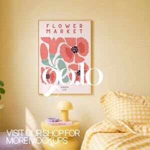 Op de afbeelding: Een ingelijste poster met een bloemenontwerp, met rode en roze bloemen met groene bladeren, en de tekst "FLOWER MARKET SWEDEN 2025." Een gele bijzettafel met een lamp en boeken staat voor een gele muur. De tekst "VISIT OUR SHOP FOR MORE MOCKUPS" staat onderaan.