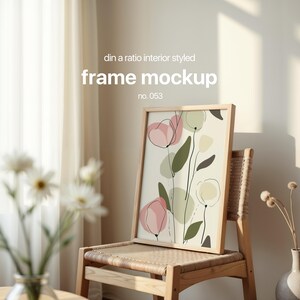 May include: A wooden frame with a print of abstract pink and green flowers on a white background. The frame is sitting on a wooden chair with a woven seat.