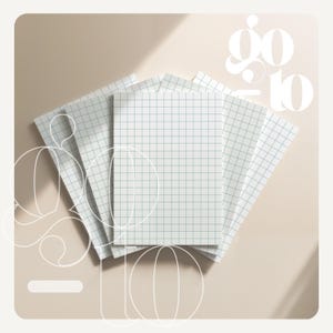 May include: A stack of white notebooks with a grid pattern and the words "go to" in a stylized font. The notebooks are arranged in a fan shape on a light beige surface.