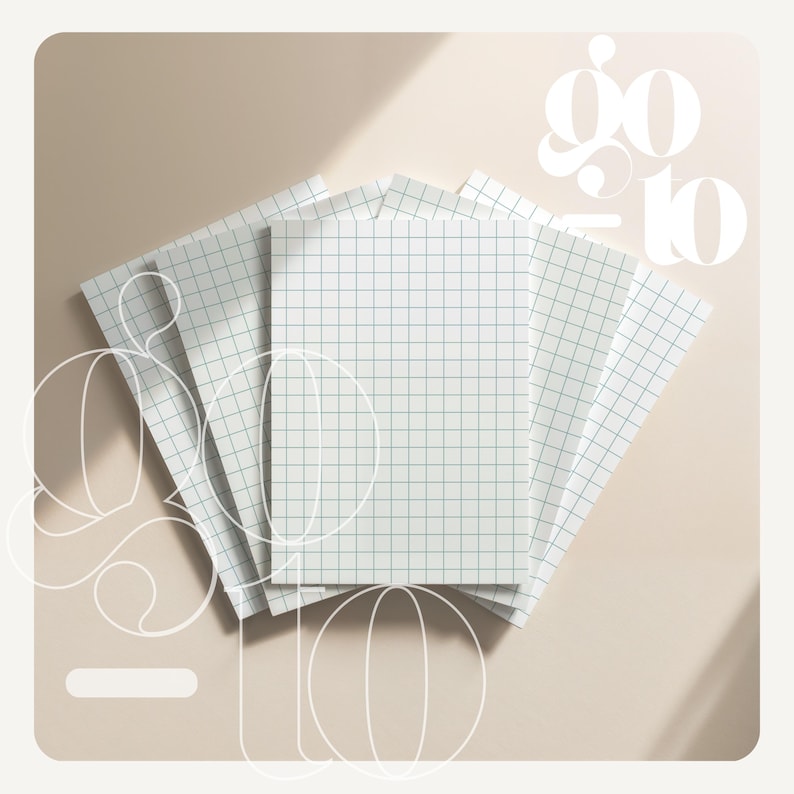 May include: A stack of white notebooks with a grid pattern and the words "go to" in a stylized font. The notebooks are arranged in a fan shape on a light beige surface.