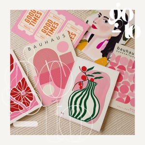 May include: A collection of art prints and tickets with a retro aesthetic. The prints feature abstract designs, a portrait, and a vase with a floral arrangement. The color palette includes pink, red, and green hues. The tickets read "GOOD TIMES".