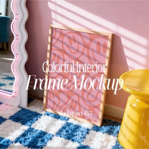 May include: A framed art print with a pink and orange smiley face pattern, leaning against a pink wall. The frame is light wood. The text "Colorful Interior Frame Mockup" and "Mockup no. 483" are visible on the print. A yellow stool and a white wavy mirror are also in the image.