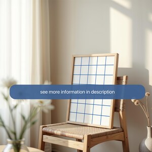 May include: A wooden frame with a white background and a blue grid pattern. The frame is sitting on a wooden chair with a woven seat.