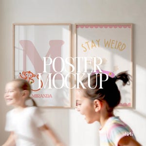 May include: Two framed posters with light wood frames. One poster features a pink letter "M" with a monkey illustration and the name "MIRANDA". The other poster says "STAY WEIRD" in gold lettering. The image is a poster mockup.