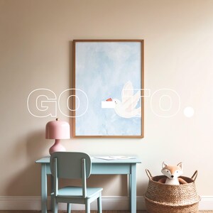 May include: A light blue desk with a pink lamp and a framed watercolor painting of a white bird flying in a blue sky. A wicker basket with a stuffed fox toy sits on the floor next to the desk.
