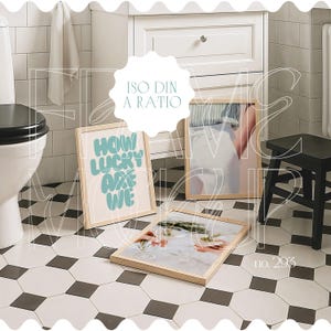 Peut inclure: Trois impressions encadrées dans un décor de salle de bain. Les impressions sont dans des cadres en bois et présentent des motifs différents. L'impression de gauche dit "How lucky are we". L'impression du milieu est un portrait d'une personne portant une chemise blanche. L'impression de droite est une photo d'une surface blanche avec des plantes vertes.