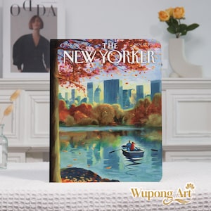 May include: A notebook featuring a cover illustration of The New Yorker magazine. The artwork depicts a serene lake scene with a rowboat, autumn foliage, and a city skyline in the background. The cover includes the magazine's logo and the date November 12, 2018.