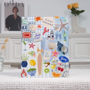 May include: A decorative notebook with a collage of beach-themed stickers, including a lobster, starfish, surfboard, and the words "Surf Club" and "East Coast". The background features a blue and white gingham pattern.