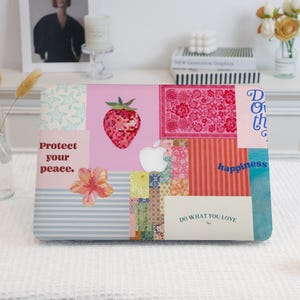 May include: A pink laptop skin with a patchwork design featuring a strawberry, flowers, and various patterns. The skin has text that reads "Protect your peace", "Do what you love", and "Happiness".