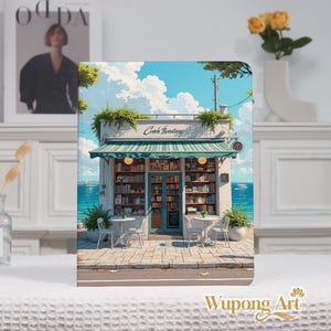 May include: A notebook featuring an illustration of a quaint bookstore by the sea. The shop has a green and white striped awning, with tables and chairs outside. The sky is blue with fluffy white clouds. The text "Covek Bookstore" is above the awning.